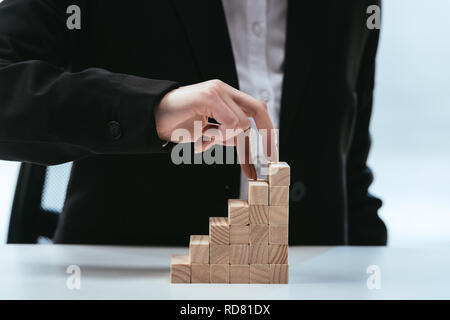 Vista ritagliata della donna che cammina con le dita su blocchi di legno che simboleggia la scaletta di carriera Foto Stock