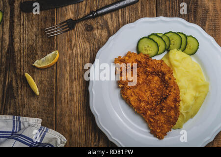 Chicken fried schnitzel con purè di patate e limone sul tavolo di legno Foto Stock