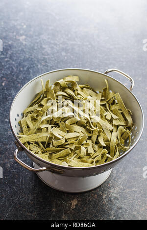 Materie pasta italiana. Asciugare le tagliatelle con spinaci nel colapasta. Foto Stock