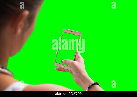 Ragazza utilizzare smart phone. Schermo isolato e lo sfondo in verde per mockup. Foto Stock