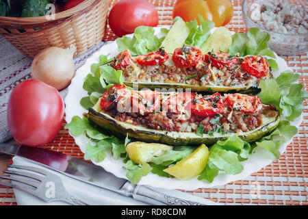 Zucchine su una piastra farcite con carne macinata e verdure con patate e insalata verde. Vista superiore Foto Stock