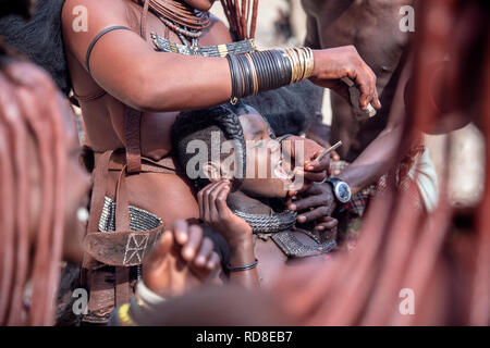 Himba dimostrando come essi rimuovere bambino denti di fondo - Damaraland, Namibia, Africa Foto Stock