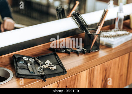 Vista ravvicinata di vari strumenti professionali sul ripiano di legno nel salone di bellezza Foto Stock