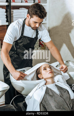 Bel giovane parrucchiere lavare i capelli alla bella donna nel salone di bellezza Foto Stock