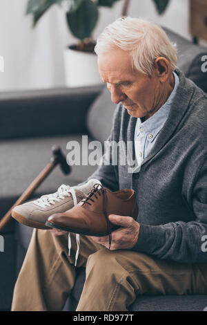 Senior uomo scegliendo tra classico e moderno scarpe Foto Stock