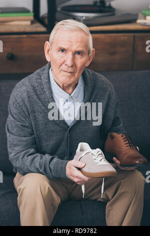 Uomo in pensione la scelta tra classico e moderno scarpe Foto Stock
