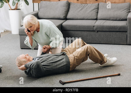 Senior donna tenendo la mano di morire uomo vecchio con bastone Foto Stock