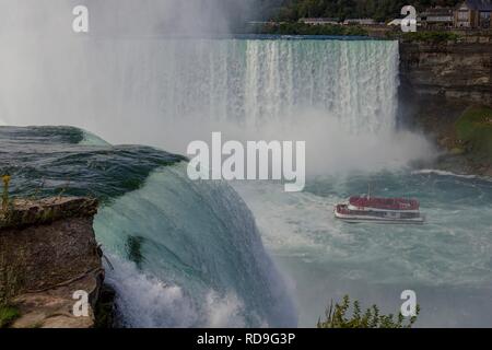 Una vista delle cascate del Niagara negli Stati Uniti lato con una barca piena di turisti per ottenere una vista ravvicinata delle cascate. Foto Stock