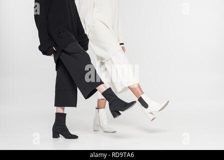 Immagine ritagliata multiculturale di donne in bianco e nero vestiti a piedi su bianco Foto Stock