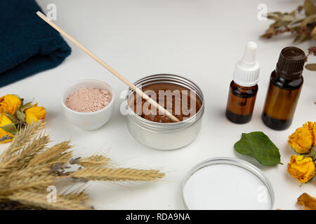 Botanico aromatico cosmetici. Le erbe aromatiche essiccate fiori miscela, fango facciale della maschera di argilla, oli, applicazione a pennello. A base di erbe olistico skincare bellezza hack Foto Stock