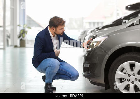 L'acquirente della vettura pensa in concessionaria auto. Un uomo guarda all'auto. Foto Stock