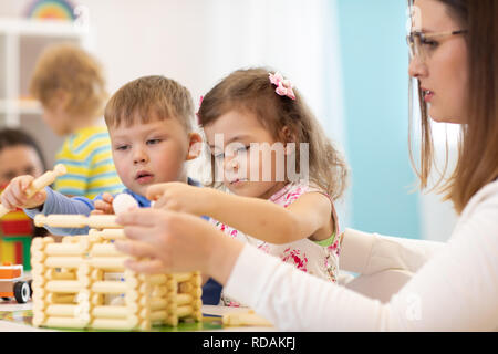 I bambini e l'asilo nido insegnante costruzione casa giocattolo in un kindergarten Foto Stock