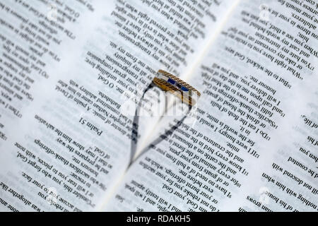 L'anello di matrimonio e a forma di cuore ad ombra su una Bibbia Foto Stock