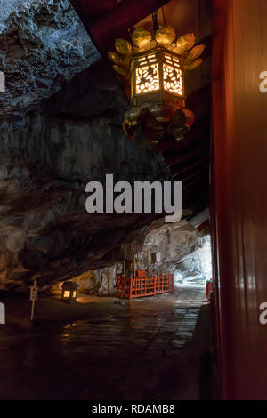 Miyazaki, Giappone - 6 Novembre 2018: ingresso al Santuario Udo impostato in una grotta sul lato di una scogliera illuminata da una lanterna Foto Stock