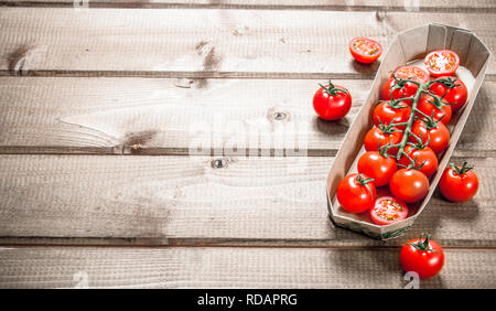 Freschi pomodori ciliegia nel vassoio. Su uno sfondo di legno. Foto Stock