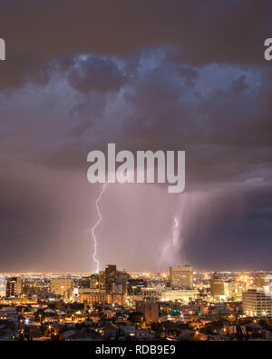 Il cloud e la messa a terra il fulmine colpisce un paesaggio urbano dietro il El Paso, Texas skyline del centro, lungo la US-frontiera messico Foto Stock