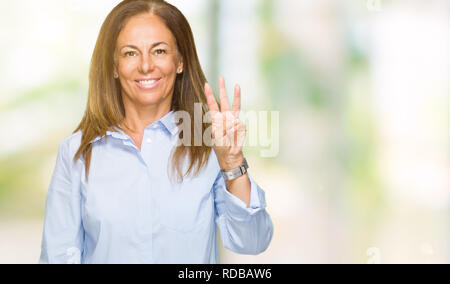 Bella Età media business donna adulta su isolati che mostra sfondo e rivolta verso l'alto con le dita in numero tre mentre sorridente fiducioso e contento Foto Stock