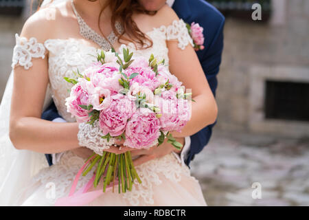 Wedding bouquet di peonie rosa nelle mani della sposa Foto Stock