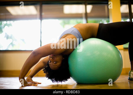 Giovane donna stretching su una palla ginnica. Foto Stock
