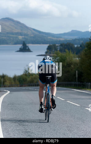 Ciclista sulla A86 passando loch laggan Highlands della Scozia Foto Stock