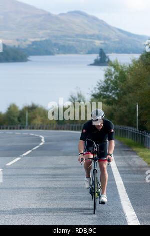 Ciclista sulla A86 passando loch laggan Highlands della Scozia Foto Stock