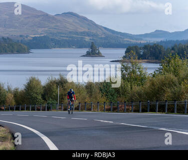 Ciclista sulla A86 passando loch laggan Highlands della Scozia Foto Stock