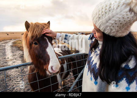 Ragazza petting adorabile cavallo islandese su Islanda viaggio su strada Foto Stock