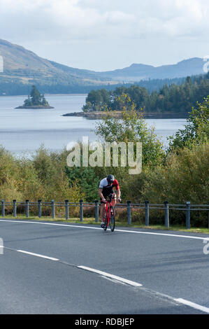 Ciclista sulla A86 passando loch laggan Highlands della Scozia Foto Stock