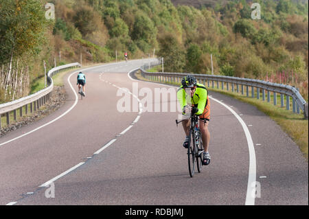 Ciclista sulla A86 passando loch laggan Highlands della Scozia Foto Stock