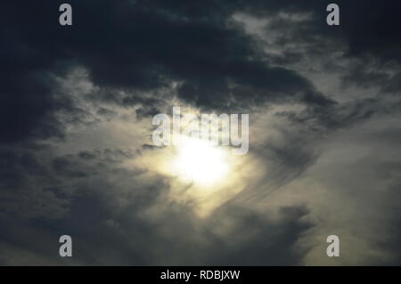 Sun dietro dark cloud simile a occhio il cielo Foto Stock