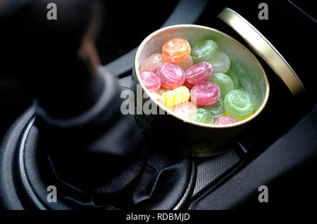 I dolci di viaggio nel round di stagno metallico sul cruscotto di automobile Foto Stock
