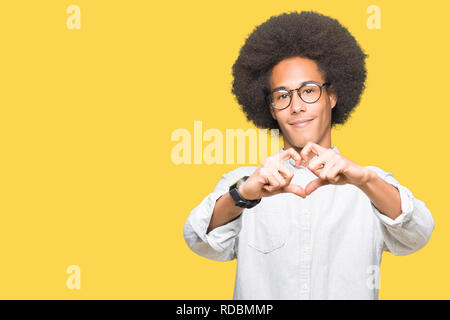 Giovane americano africano uomo con capelli Afro indossa occhiali sorridente in amore che mostra il simbolo del cuore e la forma con le mani. Concetto romantico. Foto Stock