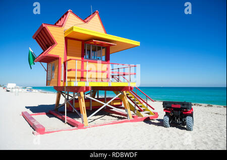 Vista vuota di un colorato lifeguard tower in piedi con una bandiera verde sulla spiaggia di Miami su un luminoso calma mattinata estiva Foto Stock
