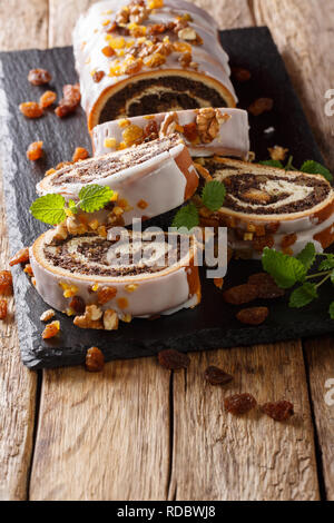 Polacca tradizionale rotolo di papavero con uvetta, noci e menta close-up su di un tavolo di legno. In verticale Foto Stock