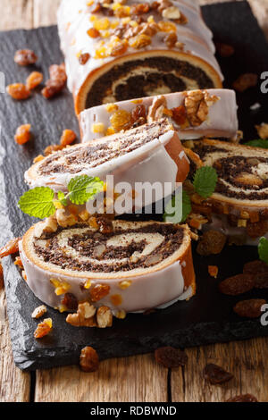 Vetrata rotolo di papavero con uvetta, noci e menta close-up su una tavola di legno verticale. Foto Stock