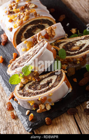 Deliziosa semi di papavero rotolo con uvetta e noci ricoperta con smalto vicino sul piano verticale. Foto Stock