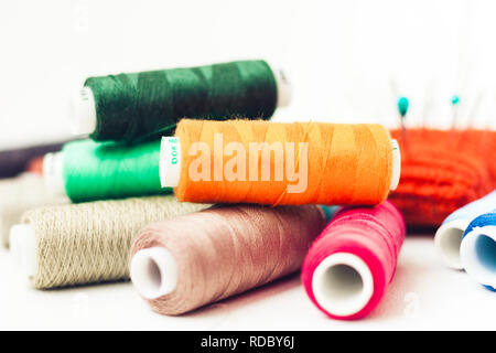 Maglia rossa pad ad ago per cucire e colorato bobine di filo su sfondo bianco Foto Stock