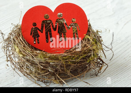 Famiglia silhouette ritagliata nel cuore di carta in un nido - Concetto di amore e famiglia Foto Stock