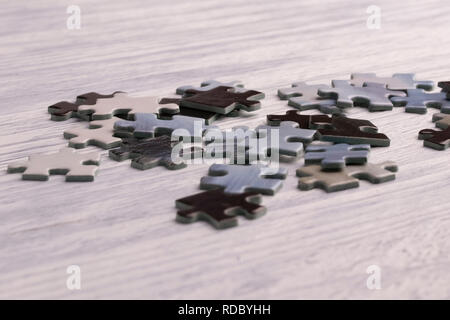 Puzzle su una bianca tavolo in legno. Sfondo sfocato. Spazio libero per l'iscrizione Foto Stock