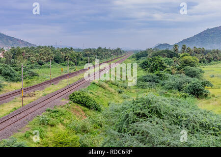 Diritta via ferroviaria va all orizzonte nel verde paesaggio sotto il cielo blu con nuvole. Foto Stock