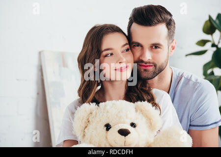 Messa a fuoco selettiva della coppia felice abbracciando Teddy bear Foto Stock