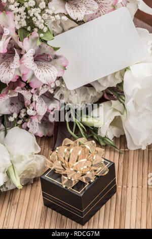 Una piccola confezione regalo e fiori con un tag vuoto sul tavolo di legno Foto Stock