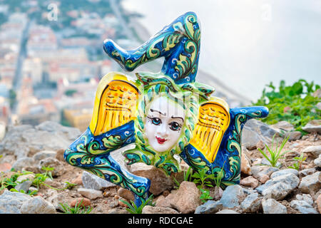 Tradizionale souvenir siciliano - Trinacria in ceramica su una scogliera sopra Cefalu. Sicilia, Italia Foto Stock