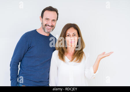 Bella la mezza età matura in amore su sfondo isolato sorridente allegro presentando e dispositivo di puntamento con il palmo della mano guardando la telecamera. Foto Stock