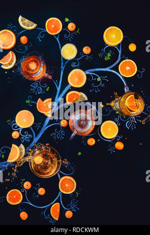 Tè al limone chalk tree con teacups, teiera e fette di arance e di limoni. Bevanda calda creative laici piatta con spruzzi su sfondo scuro con spazio di copia Foto Stock