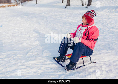 Senior donna in discesa in slittino. Donna divertirsi seduti sulla slitta in winter park. Foto Stock