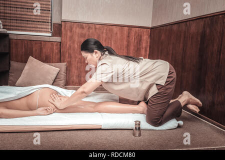 Grave massaggiatrice femmina massaggiando il suo corpo ai clienti Foto Stock