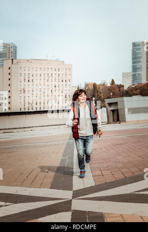 Ragazzo con gioia che corre attraverso il centro della città Foto Stock