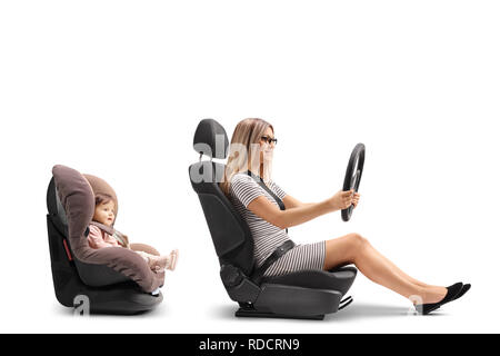 Giovane donna in un sedile di vettura foratura di un volante e una bambina strapped in un sedile di automobile isolato su sfondo bianco Foto Stock