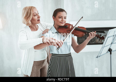 Bella ragazza positiva avente una lezione con il suo insegnante Foto Stock